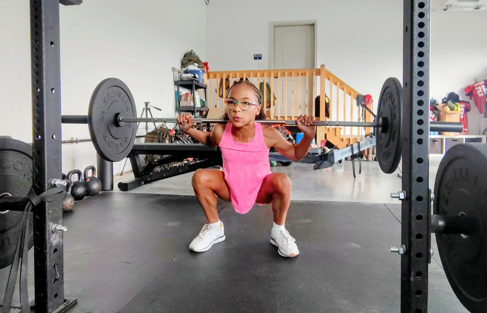 A young athlete squatting under the rig