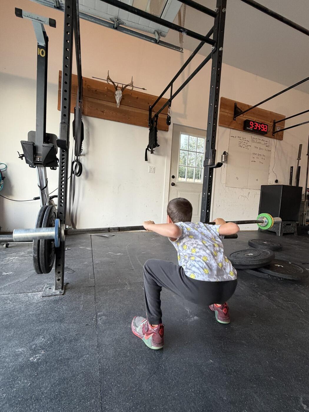 A young athlete at the bottom of an empty-bar squat